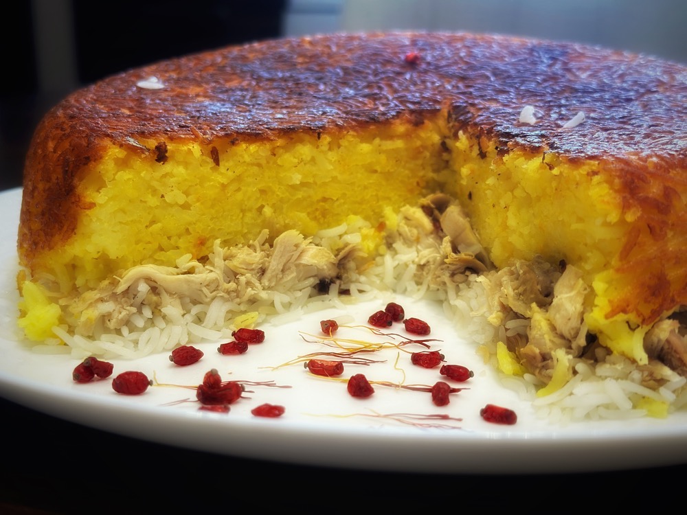 Safran-Hähnchen-Tahchin mit goldener Reiskruste, garniert mit Berberitzen und Pistazien